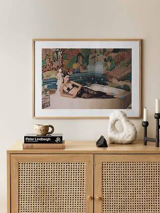 Framed fashion photo of a woman reclining on a bathtub edge before a colorful mosaic wall
