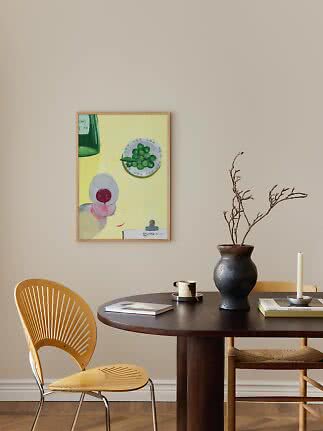 Dining nook with round dark table, chair, black vase with branches, and colorful wall art