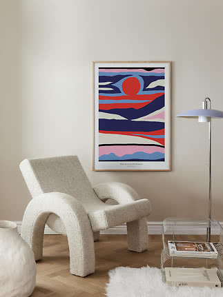 Colorful abstract framed poster above a cream armchair in a modern living room corner