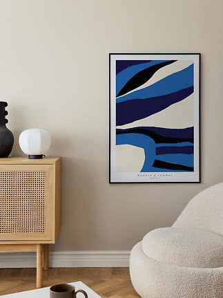 Framed abstract poster in blue, black and cream on a beige wall above a cabinet