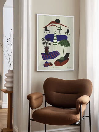 Framed colorful poster with abstract beach scene hanging above a brown armchair in a bright room