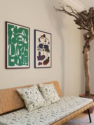 Daybed in fibra naturale intrecciata con cuscini fantasia e due poster incorniciati alla parete