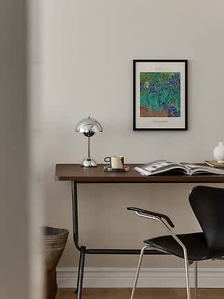Scrivania con lampada cromata, tazza, libro aperto e poster Van Gogh incorniciato a parete