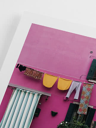 Laundry hanging on a clothesline in front of a pink building with green shutters.