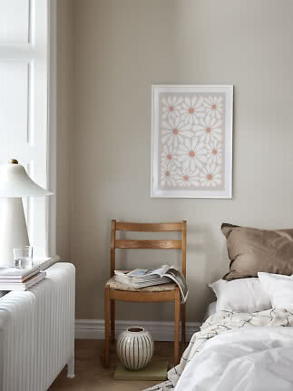 Soveværelse med blomsterplakat i hvid ramme over træstol ved seng og vindue
