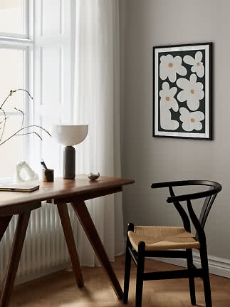 Affiche florale encadrée sur mur gris au-dessus d'un bureau et d'une chaise noire