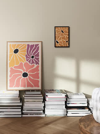 Abstrakta blomsterposters på beige vägg med travar av böcker på golvet