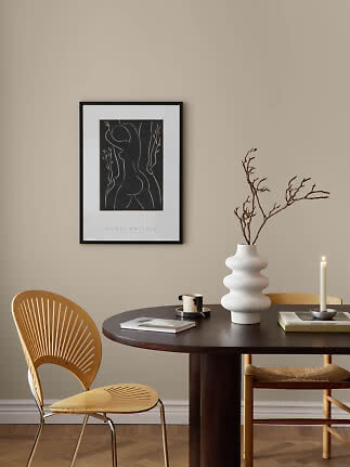 Black framed Henri Matisse poster above a dark round table with white vase, branch and candle holder