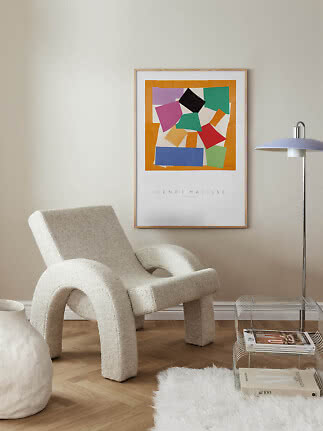 Indrammet Henri Matisse-plakat med farverige abstrakte former over en cremefarvet loungestol