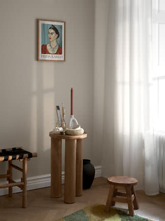 Indrammet Frida Kahlo-plakat på væg over lille træbord ved solrigt vindue