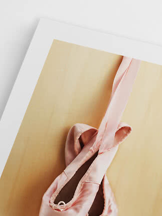 Pink ballet shoes with ribbons on a yellow background with white border