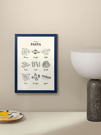 Framed pasta poster with blue frame and illustrations of different pasta shapes on a beige wall