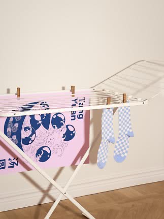 Hellblaue karierte Socken hängen auf einem weißen Wäscheständer neben einem rosa Handtuch