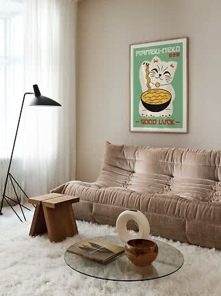 Indrammet plakat med vinkende kat og nudelskål over beige sofa i moderne stue