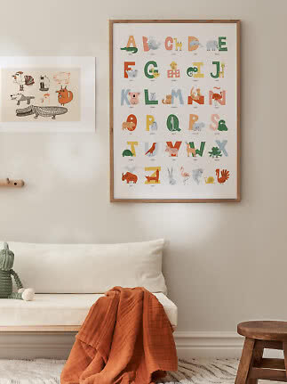 Kids room with colorful animal alphabet poster in wooden frame above a white bench