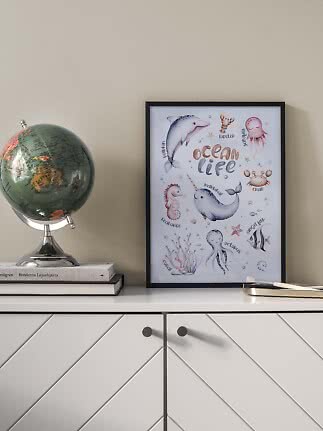 Framed ocean life poster on a cabinet beside a globe