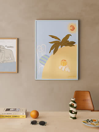Póster abstracto enmarcado con cítricos y hojas en pared beige sobre una mesa clara.