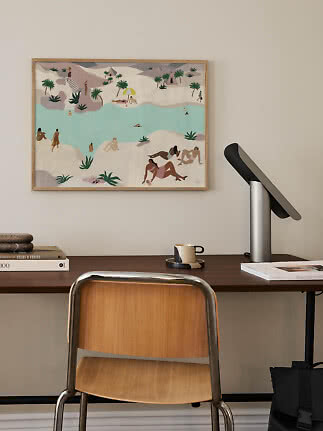 Framed beach illustration with swimmers and palm trees hanging above a desk