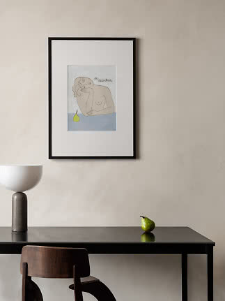 Framed art print with line drawing of a woman and pear on a light wall above a black table