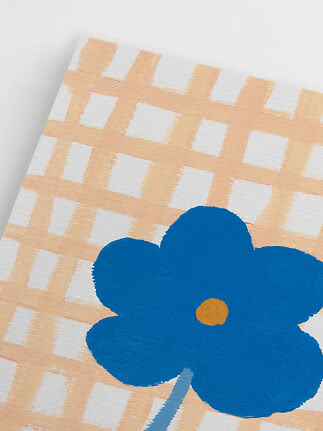 Gros plan d’une fleur bleue sur fond à carreaux blanc et pêche clair