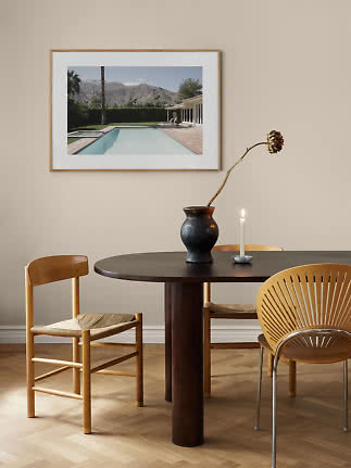 Indrammet poolfoto over rundt spisebord med stole, vase og tændt lys