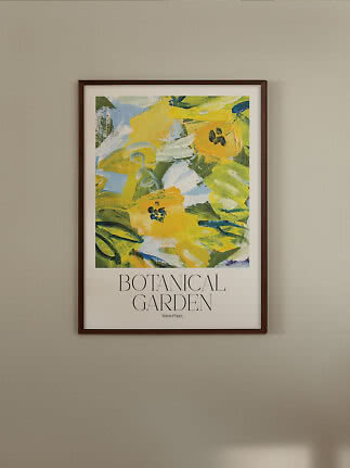 Indrammet botanisk plakat med gule blomster og teksten "Botanical Garden" på en beige væg