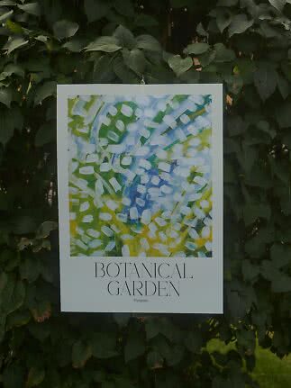 Poster Botanical Garden con arte astratta verde, blu e bianca appeso davanti a fitte foglie verdi