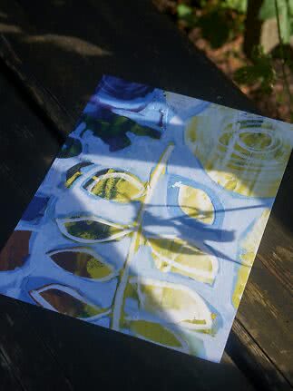 Abstract blue, white and yellow painting on a dark wooden outdoor table in sunlight