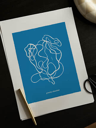 Blue art print with white abstract line drawing on desk with gold pen and black scissors