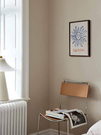 Gerahmter Kunstdruck mit blauer Sonne und Schriftzug Café du Soleil an beigefarbener Wand