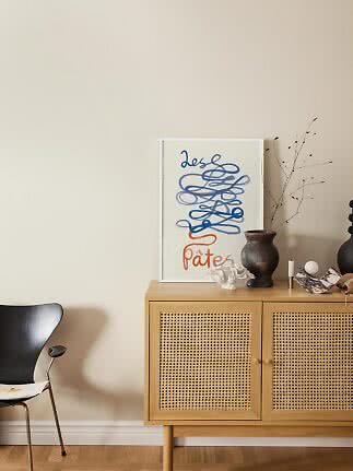 Sideboard aus hellem Holz mit Geflechtüren, Poster, dunkler Vase und Dekoobjekten