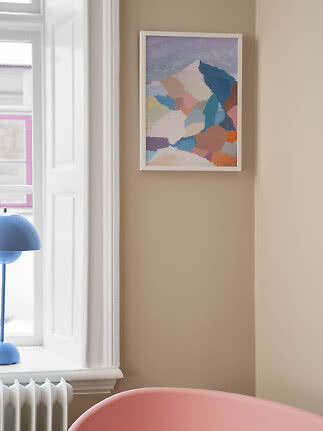 Indrammet abstrakt kunsttryk med pastelfarver på beige væg ved vindue