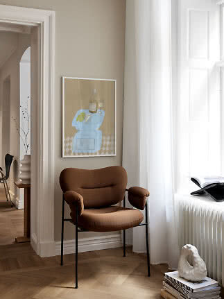 Brun polstret stol med sorte ben ved et lyst vindue i en elegant stue