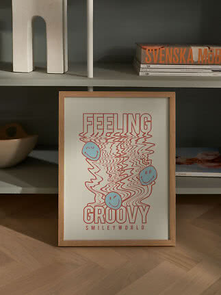 Poster SmileyWorld incorniciato con scritta "Feeling Groovy" davanti a uno scaffale