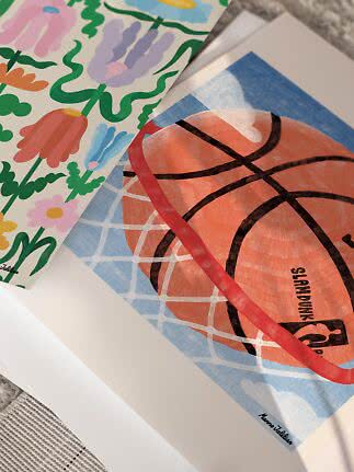Two overlapping art prints: a colorful floral design and a basketball by a hoop net.