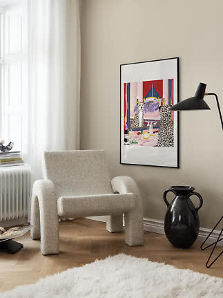 Gerahmter farbiger Kunstdruck an beige Wand über Bouclé-Sessel in heller moderner Ecke