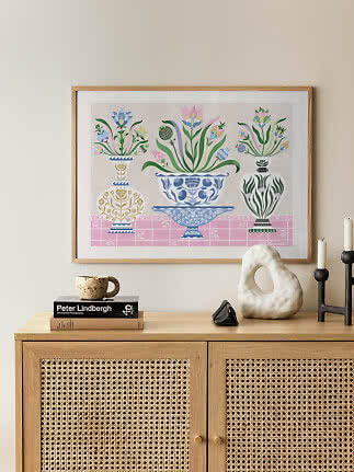Stampa incorniciata con fiori colorati in vasi decorativi sopra un mobile in legno chiaro