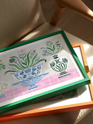 Stampa floreale con cornice verde su sedia beige, sopra una cornice arancione al sole