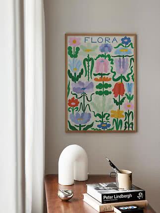 Affiche florale colorée encadrée avec le texte FLORA au-dessus d'une table en bois.