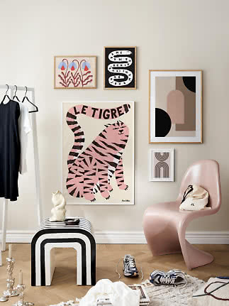 Stilvolle Ecke mit Bilderwand, rosa Stuhl, schwarz-weißem Hocker und Kleiderständer