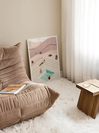 Framed art print with abstract pool scene leaning against the wall in a bright living room