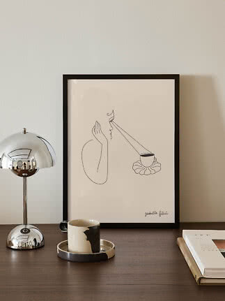 Indrammet minimalistisk stregtegning på bord med kromlampe, krus og bog