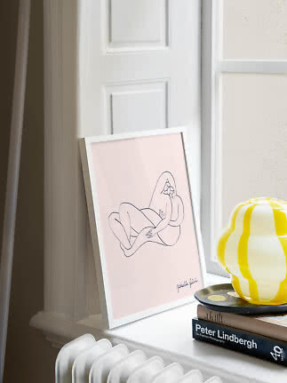 Framed minimalist line drawing on a pink background, leaning on a windowsill