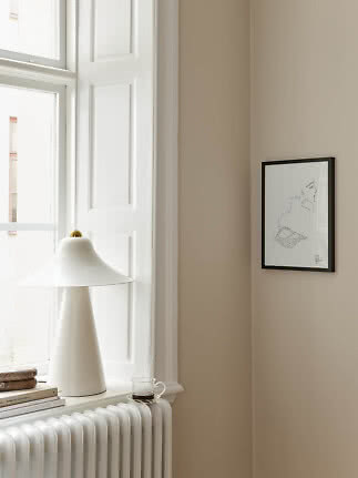 White table lamp on windowsill by radiator with framed art on beige wall