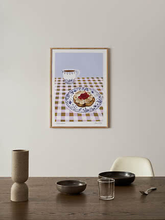 Poster incorniciato con dolce alla panna e lamponi e una tazza su tovaglia a quadri