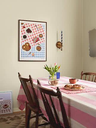 Eethoek met roze gestreept tafelkleed, houten stoelen, tulpen en bord met kaneelbroodjes.