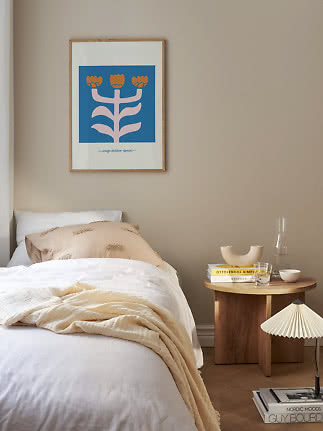 Bedroom with white bed, wooden bedside table and framed floral print on beige wall