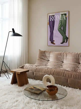 Cozy living room with beige sofa, black floor lamp, glass table and Roma poster on the wall