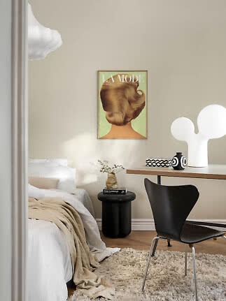 Cozy bedroom with white bed, black chair, table lamp and fashion poster on a beige wall
