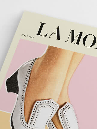 Close-up of a vintage LAMODA poster with legs in white and black high heels on a pink background